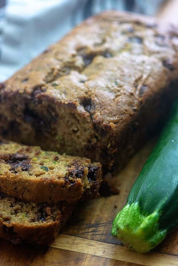 A loaf of zucchini bread on a cutting board with a few slices made in the loaf.