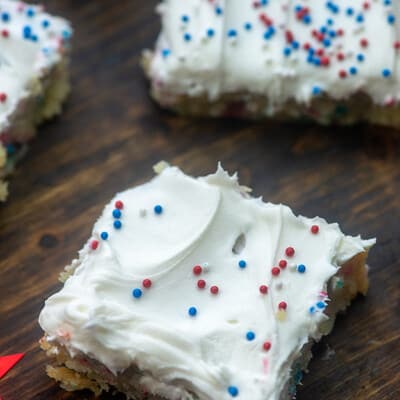 Square sugar cookie bars topped with white icing and sprinkles.