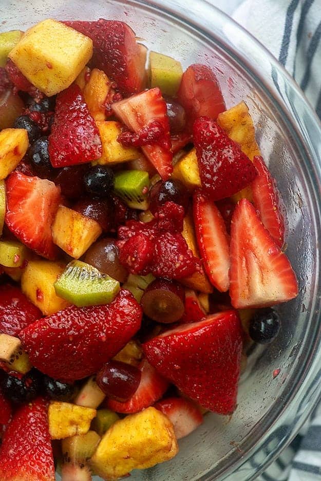 A large clear glass bowl with various fruits in it.