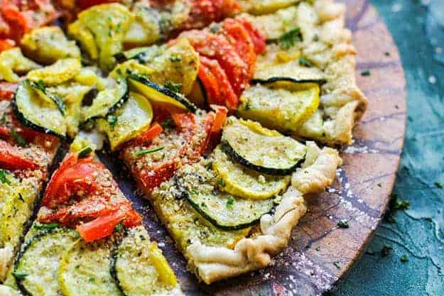 A slice of tomato tart on a pizza paddle.