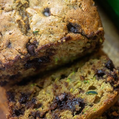 A loaf of chocolate chip zucchini bread with a slice cut away.
