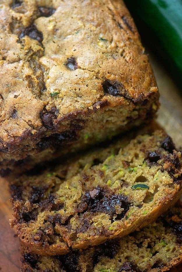 A loaf of chocolate chip zucchini bread with a slice cut away.