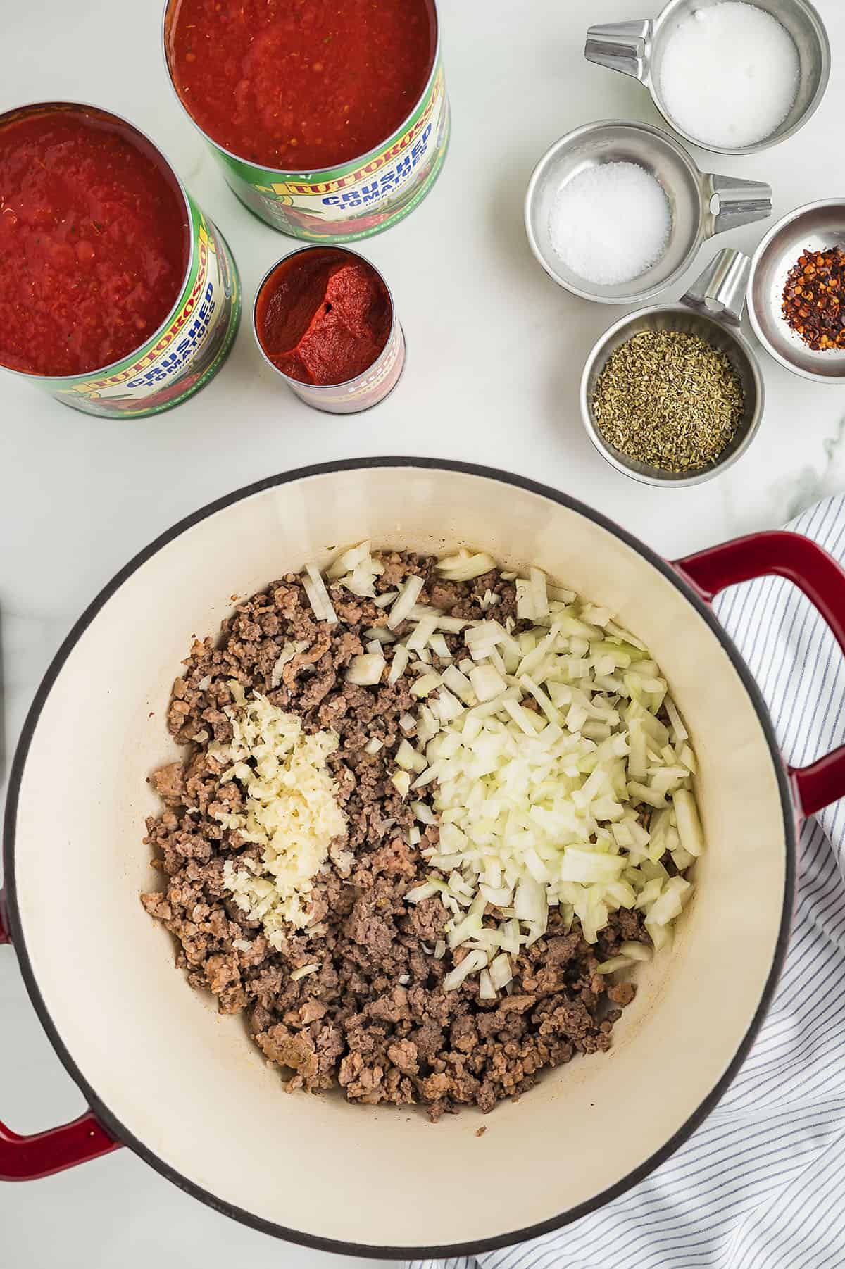 Beef and sausage in a dutch oven with garlic and onion for spaghetti sauce.