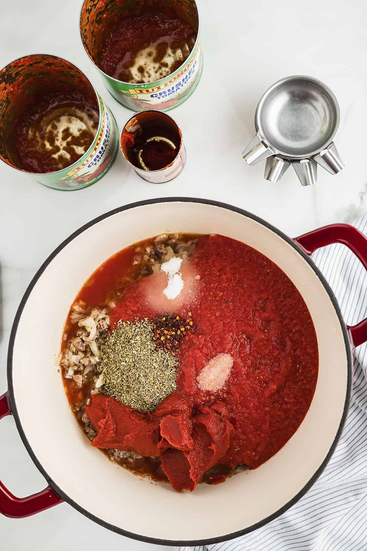 Canned tomato sauce in dutch oven with other ingredients for making homemade spaghetti sauce.