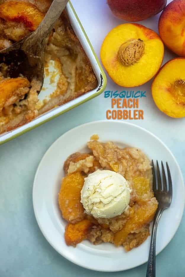 Overhead view of peach cobbler, split peaches, and baking pan. 