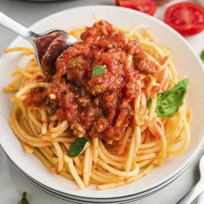 Spaghetti sauce over pasta on white plate.