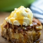 A close up of a piece of cake on a plate, with ice cream and caramel on top.