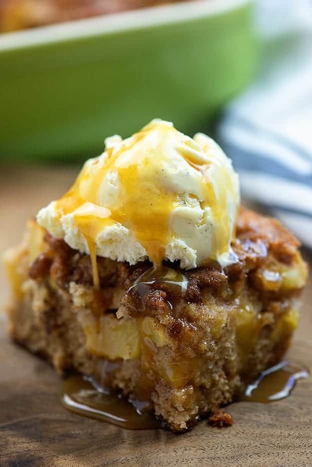 A close up of a piece of cake on a plate, with ice cream and caramel on top.