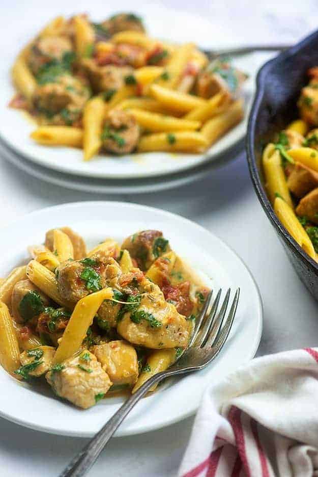 AA plate of pork pasta next to a cast iron skillet.