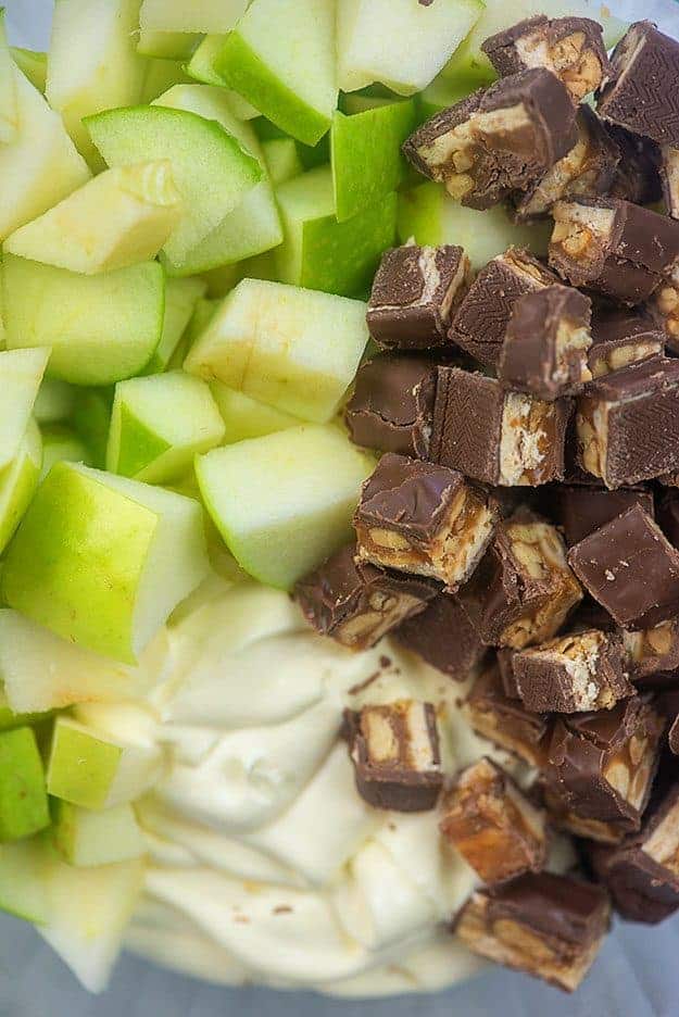 Chopped up snickers and chopped up apples up close.