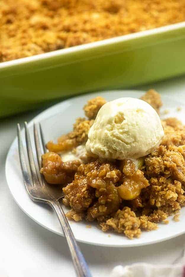 Apple crisp on a plate in front of a baking pan.