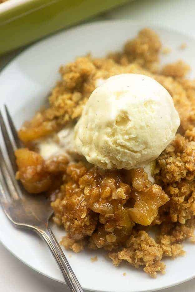 Vanilla ice cream on top of a plate of apple crisp.