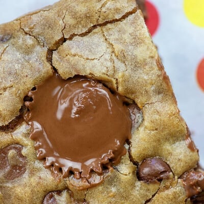 A close up of a melted Reese's peanut butter cup in the middle of a blondie.