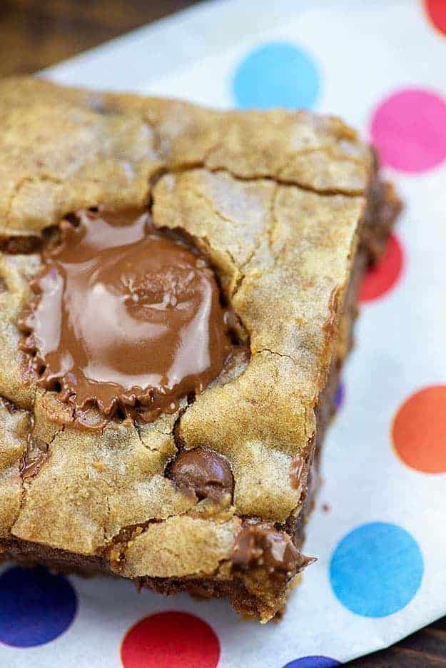 A mini peanut butter cup starting to melt in a square of a peanut butter brownie.