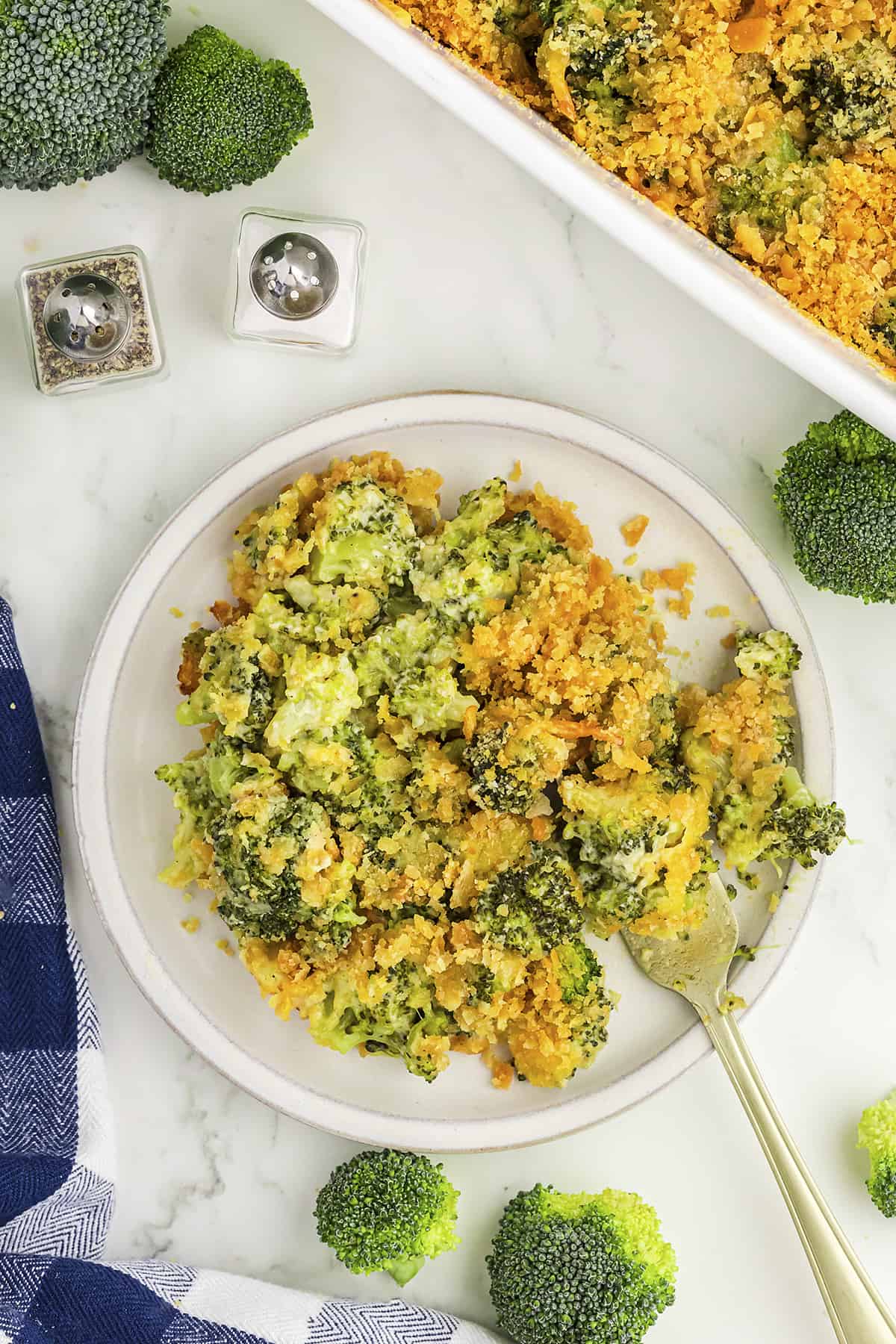 Broccoli cheese casserole on white plate with fork.