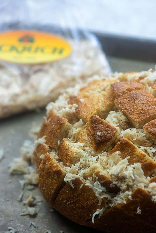 A close up of a loaf of cooked bread with cold swiss cheese on top.