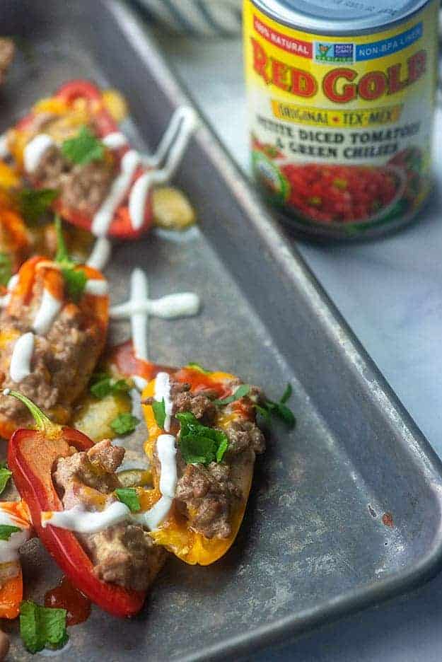 A close up of a tray of food, with Peppers and a can of diced tomatoes in the background.