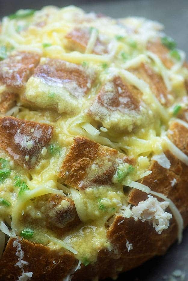 A close up of a loaf of cooked bread with melted swiss cheese on top.