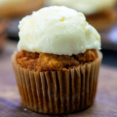 A wrapped cupcake with white frosting on top.