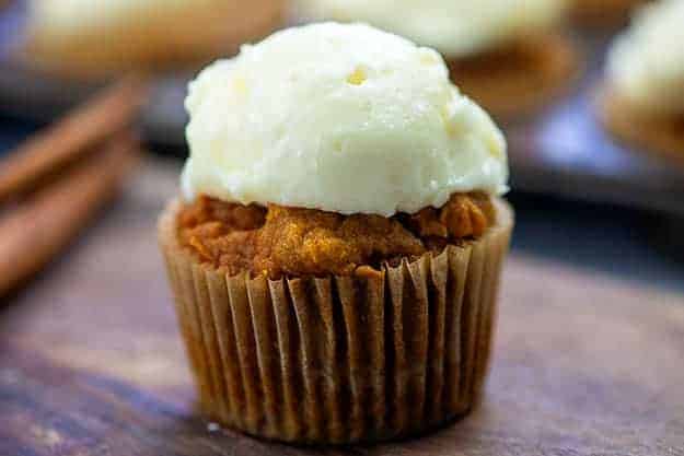 A wrapped cupcake with white frosting on top.