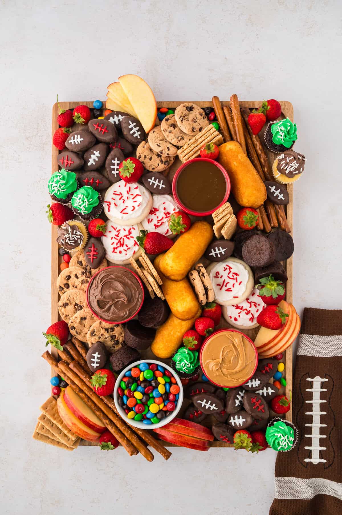 Football dessert board filled with cookies, cupcakes, and candy.