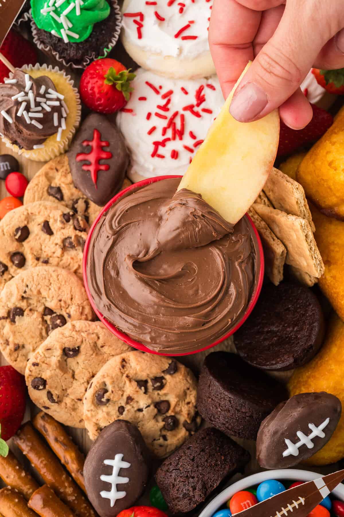 Apple slice being dipped in Nutella.