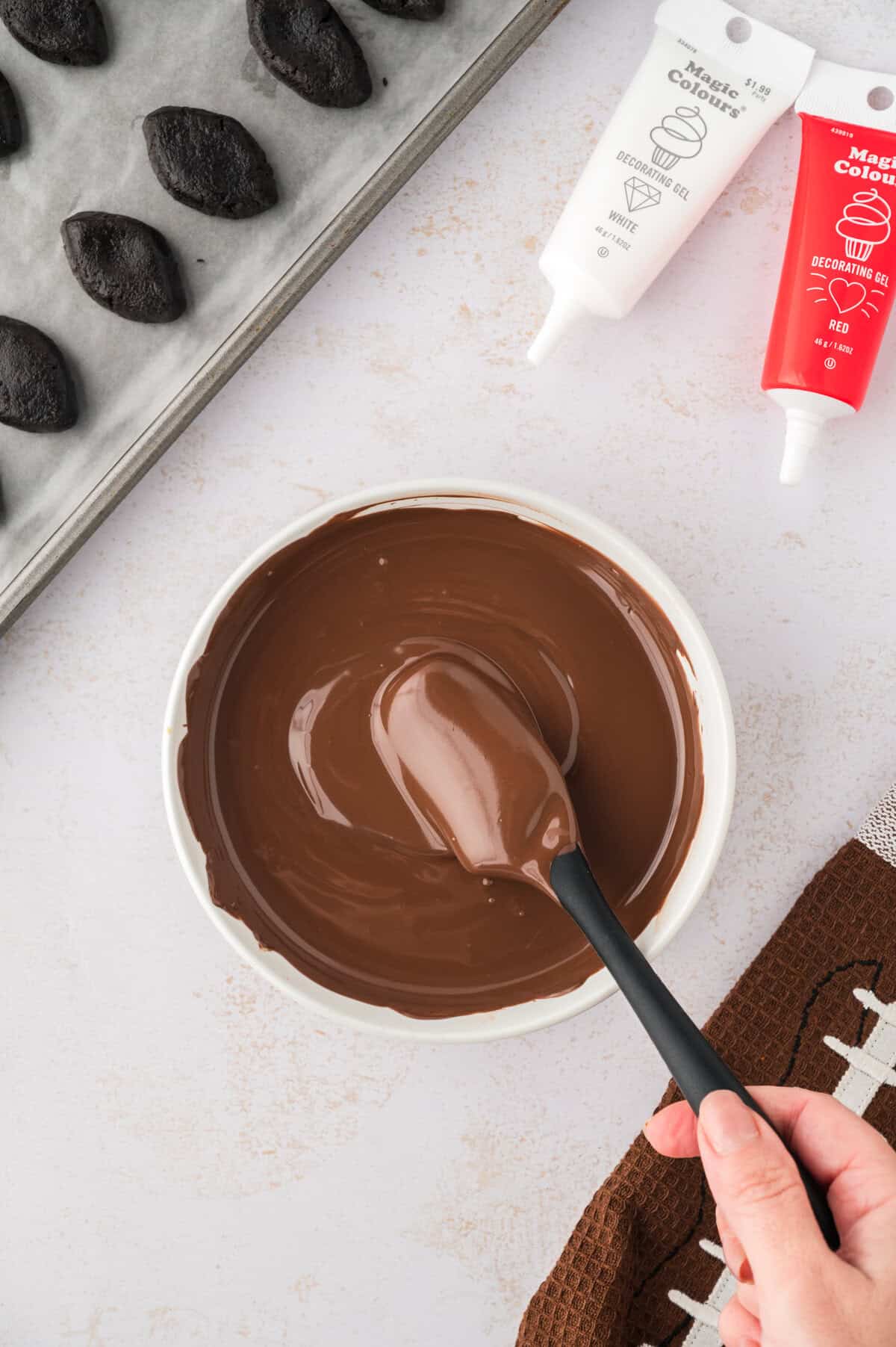 Oreo football balls being dunked in chocolate.