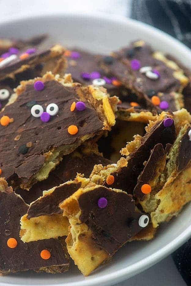 A stack of toffee topped with melted chocolate with a candy face on it.