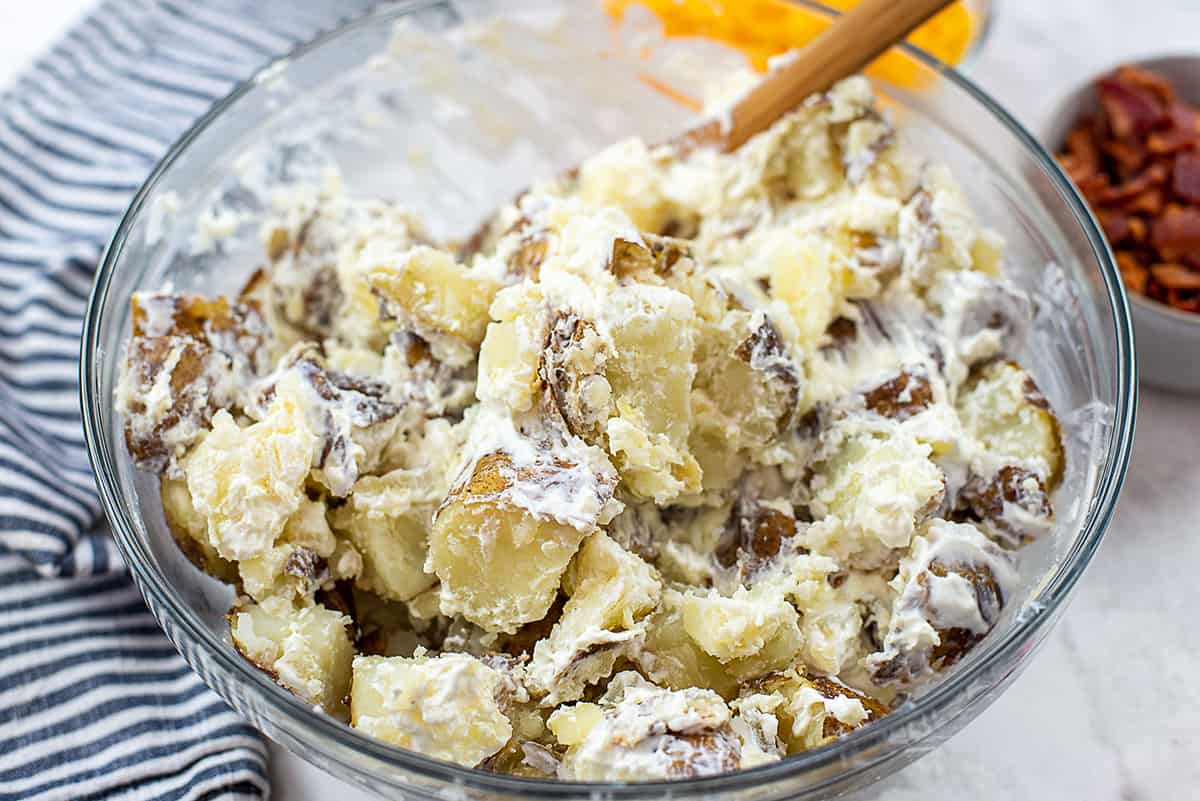 potatoes coated in sour cream in mixing bowl.