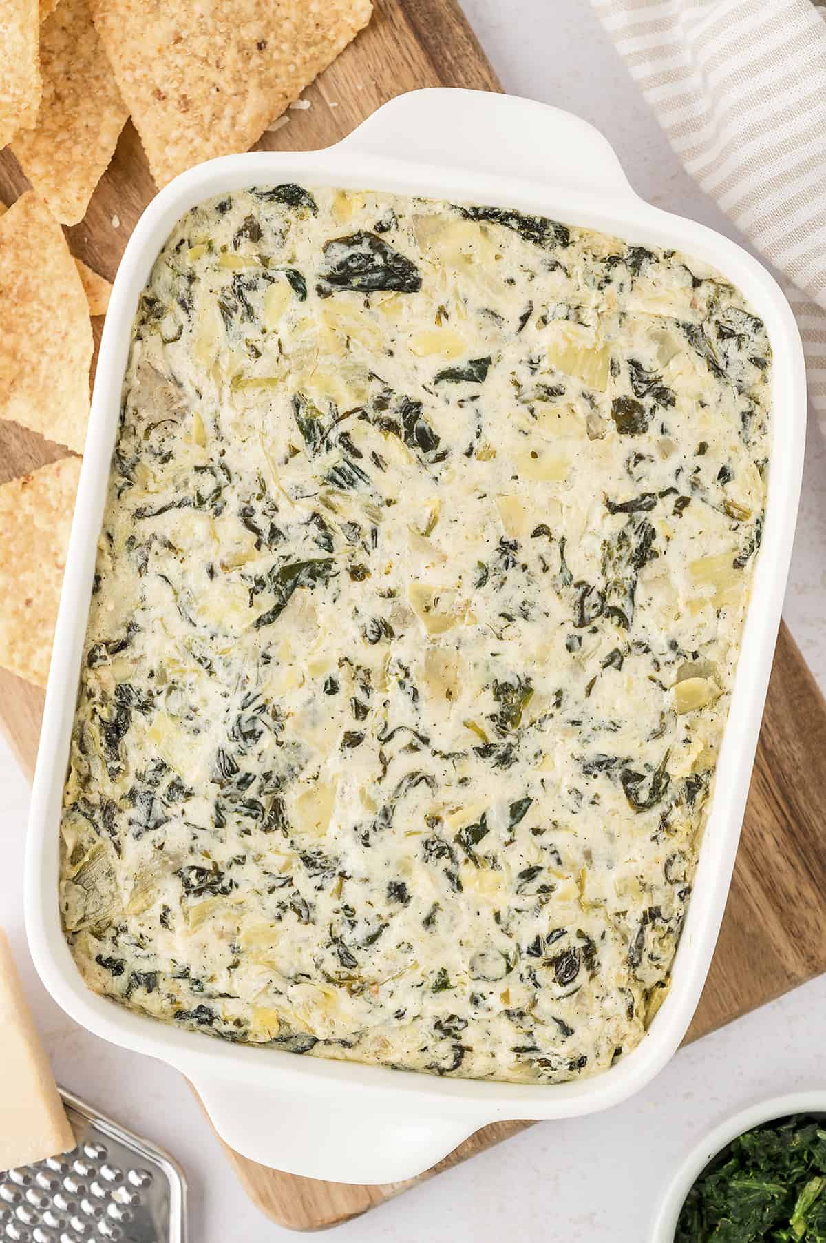 Baked spinach artichoke dip in white dish.