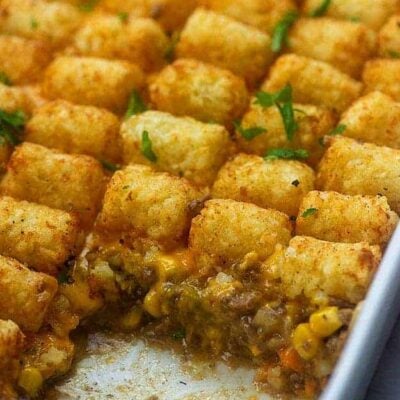 A white baking sheet of tater tots with a serving missing.