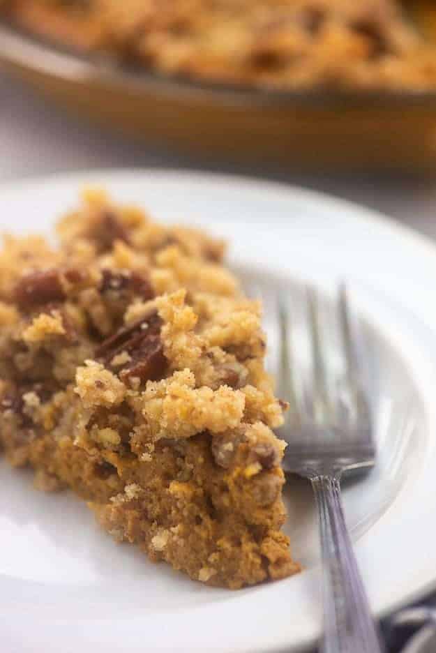 A slice of keto pumpkin pie on a white plate next to a fork.