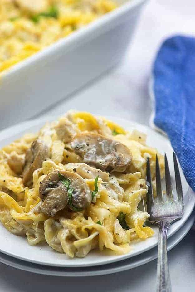 A white plate of noodles topped with mushrooms.