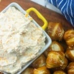 Beer cheese dip in a baking pan with a pile of pretzel bites next to it.