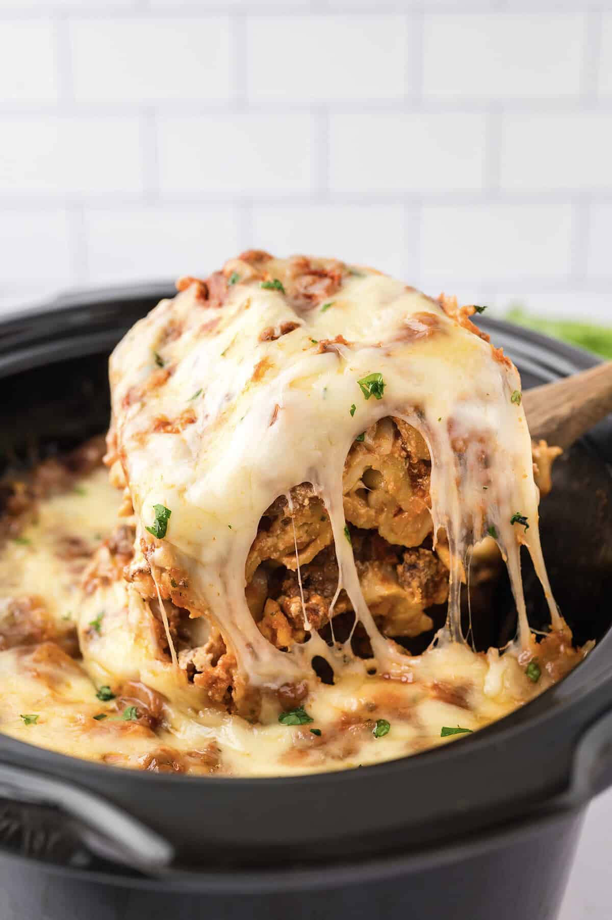 Cheesy slice of lasagna being taken out of the crockpot.