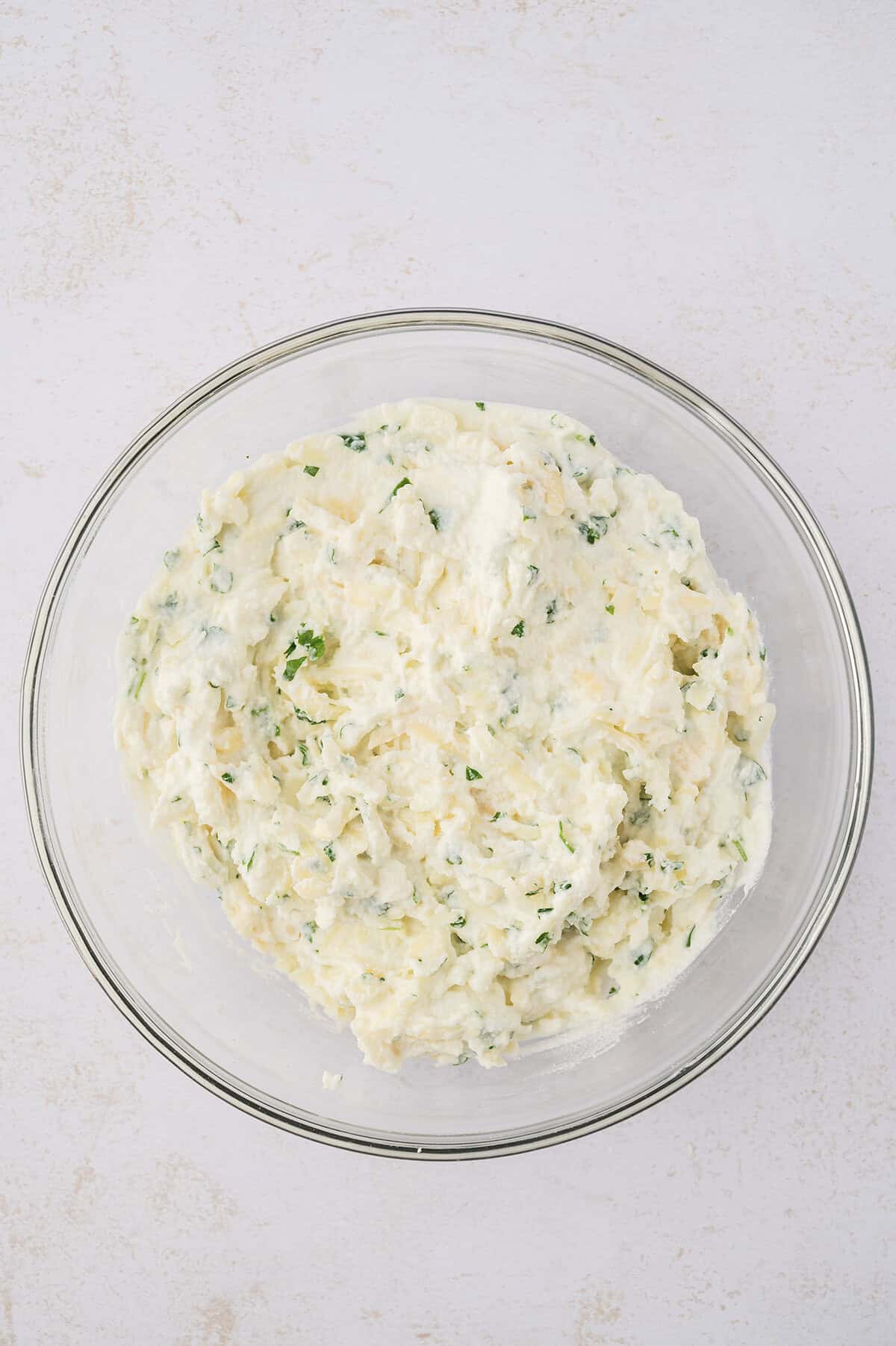 Ricotta cheese mixture for lasagna in a glass bowl.