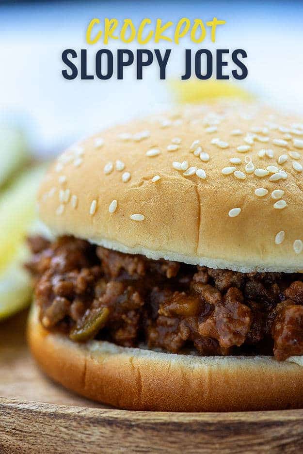 A close up of a sloppy joe sandwich sitting with a sesame seed bun.