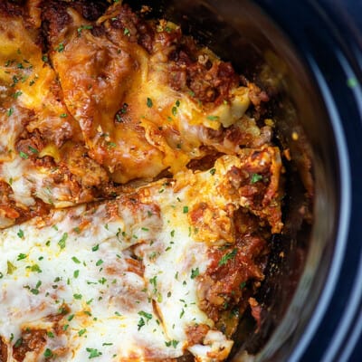 Lasagna in a slow cooker cut into four triangle pieces.