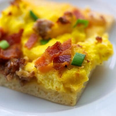 sausage and bacon breakfast pizza on white plate
