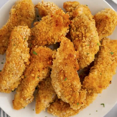 Oven fried chicken tenders on white plate.