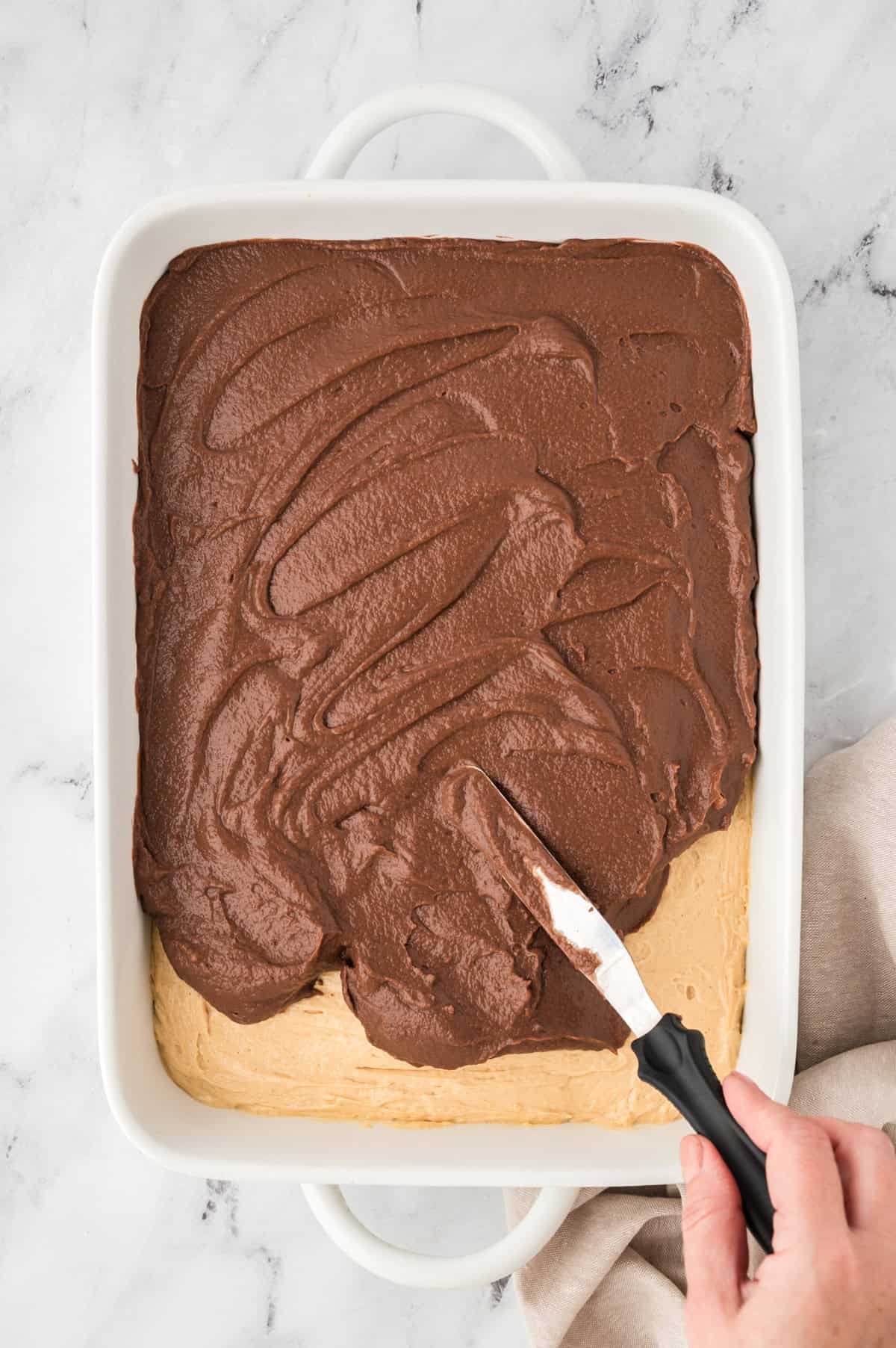 Chocolate pudding being spread over peanut butter layer.