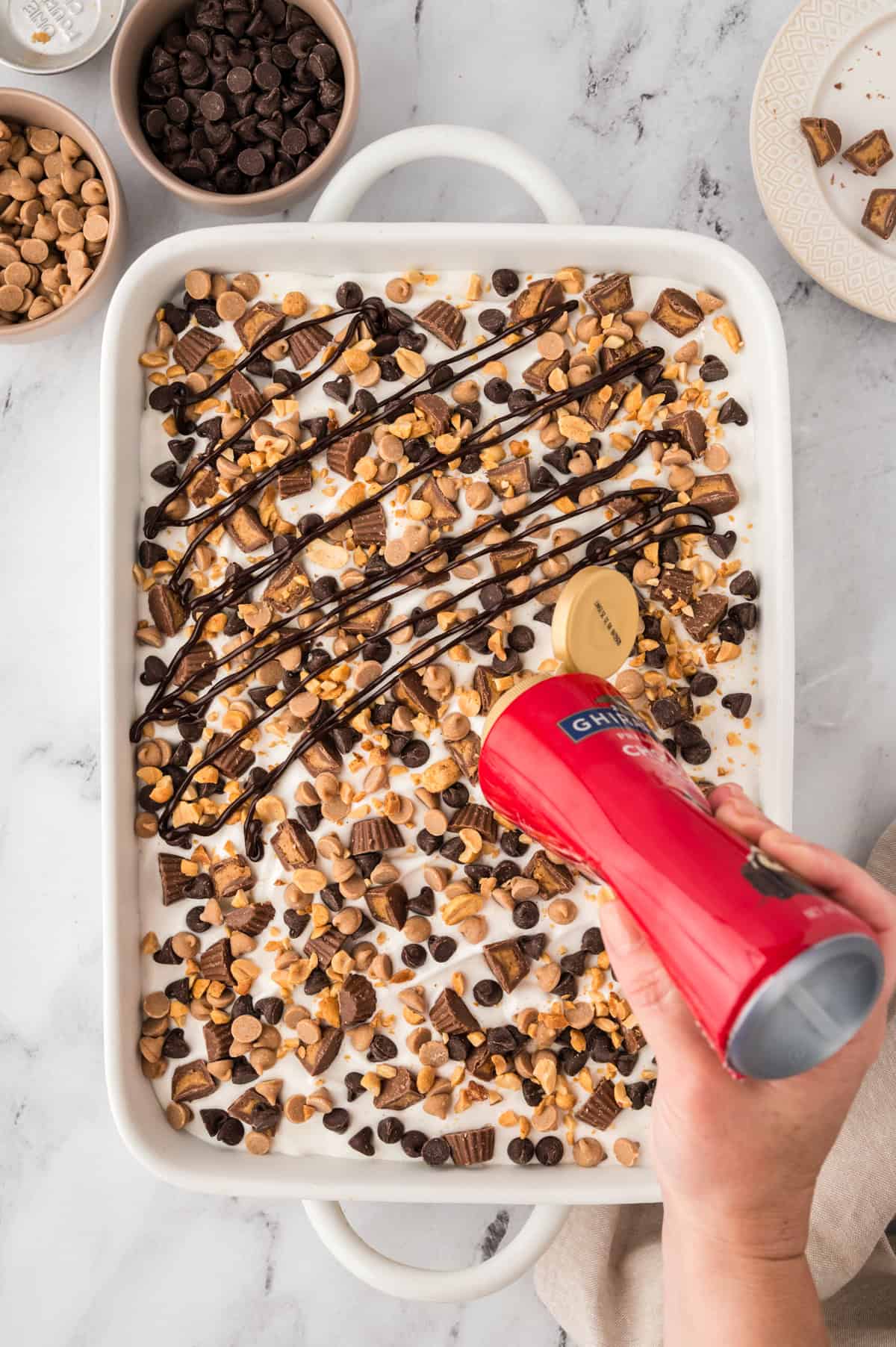 Chocolate syrup being drizzled over peanut butter lasagna recipe.