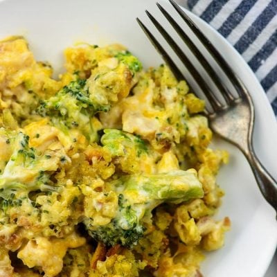 A white plate with cheesy broccoli on it.