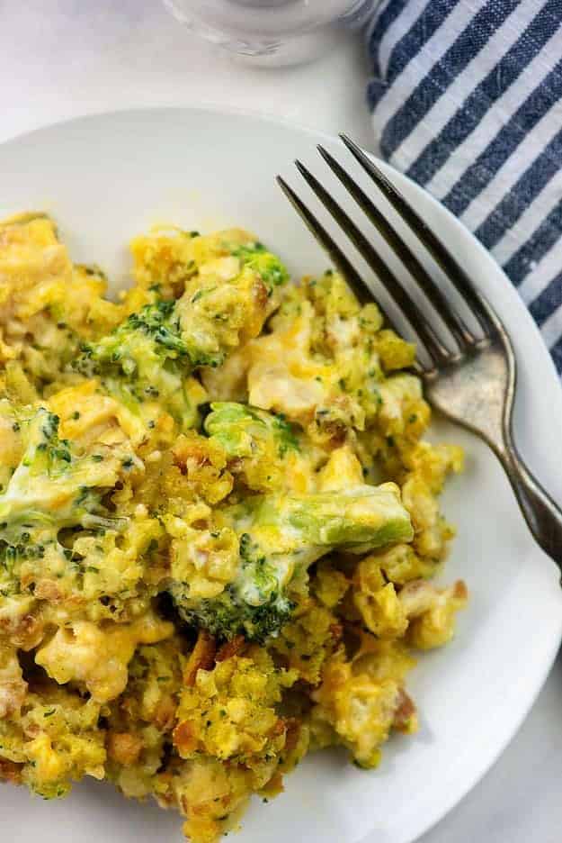 A white plate with cheesy broccoli on it.