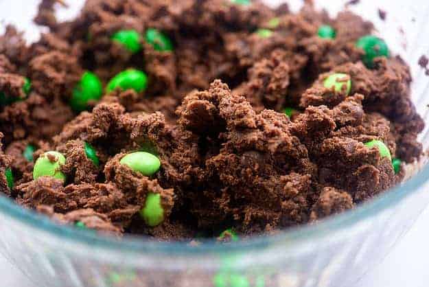 chocolate cookie dough with green m&ms in glass bowl