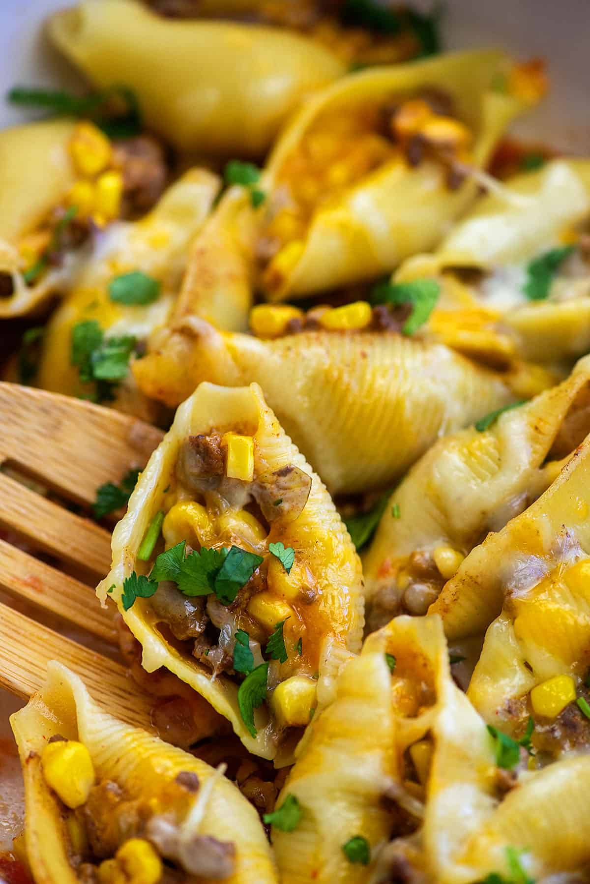 stuffed pasta shells in pan with wooden spoon.