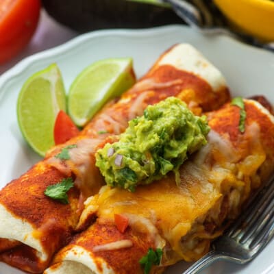 ground beef enchilada recipe on white plate with guacamole