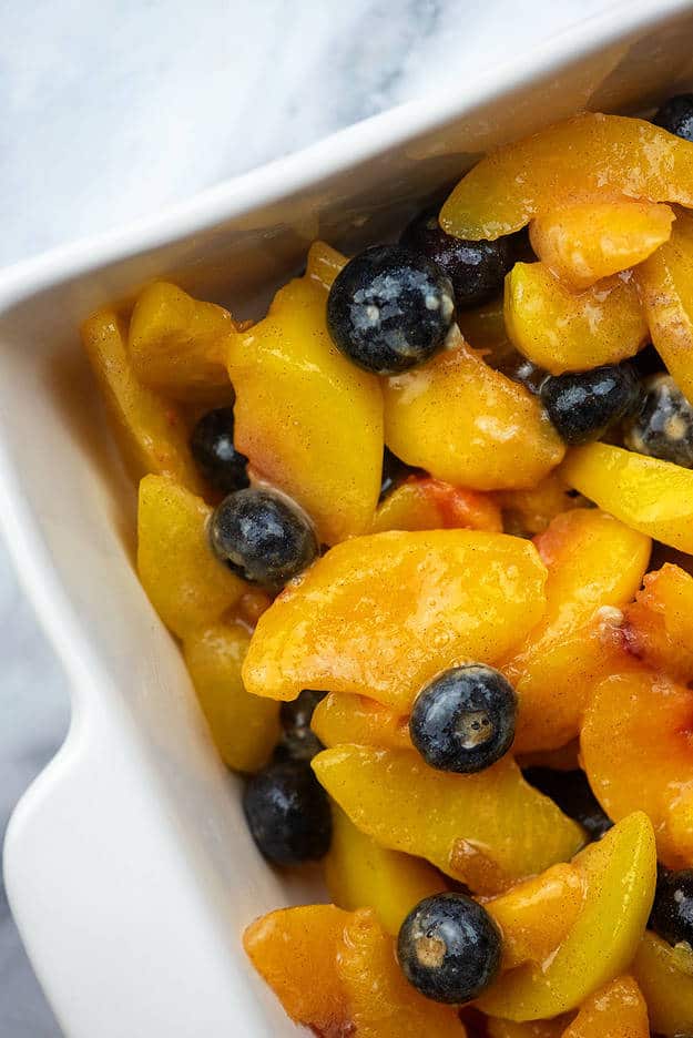 peach and blueberry filling in white baking dish