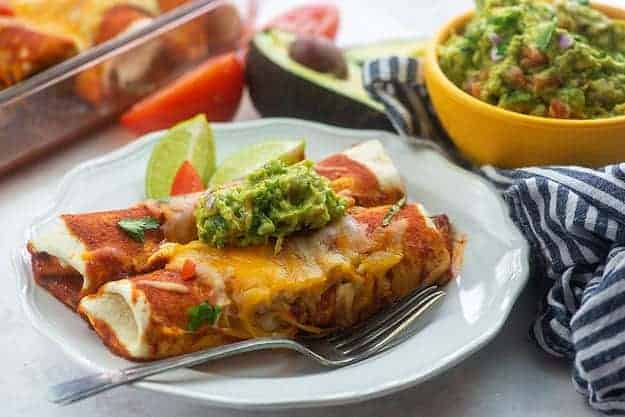 ground beef enchilada recipe on white plate with guacamole