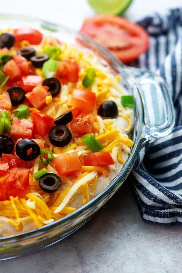 seven layer dip recipe in glass pie plate with olives on top